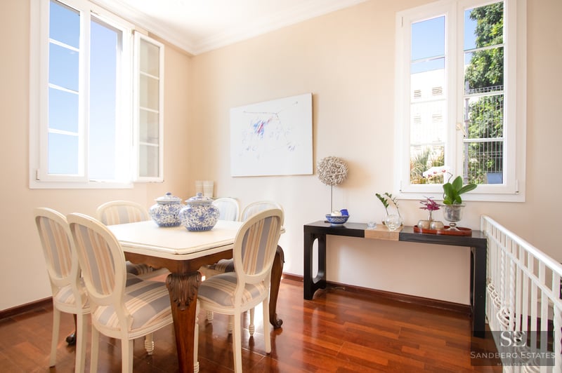 Helles Esszimmer mit weißem Tisch, gestreiften Stühlen, Parkettboden und großen Fenstern.