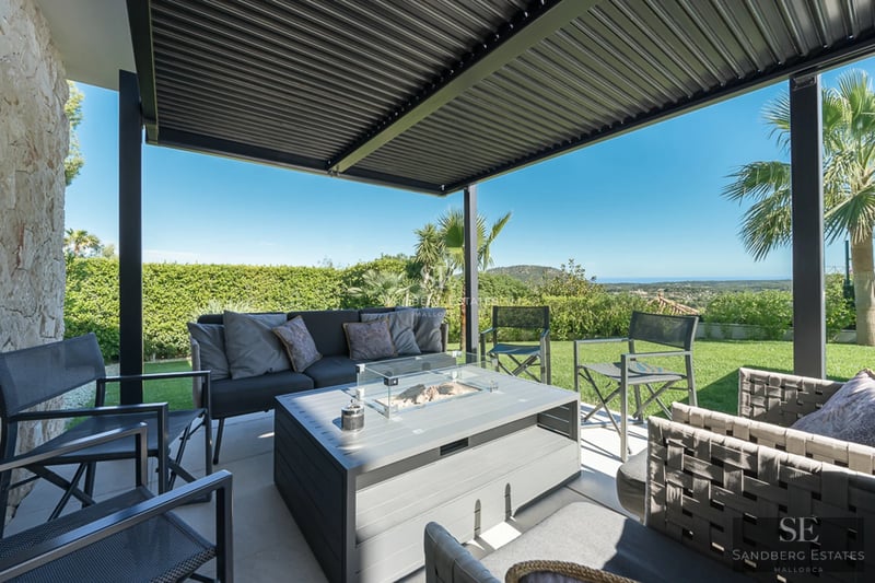 Spacious balcony with panoramic sea views. Modern, minimalist design with glass railing and outdoor furniture.