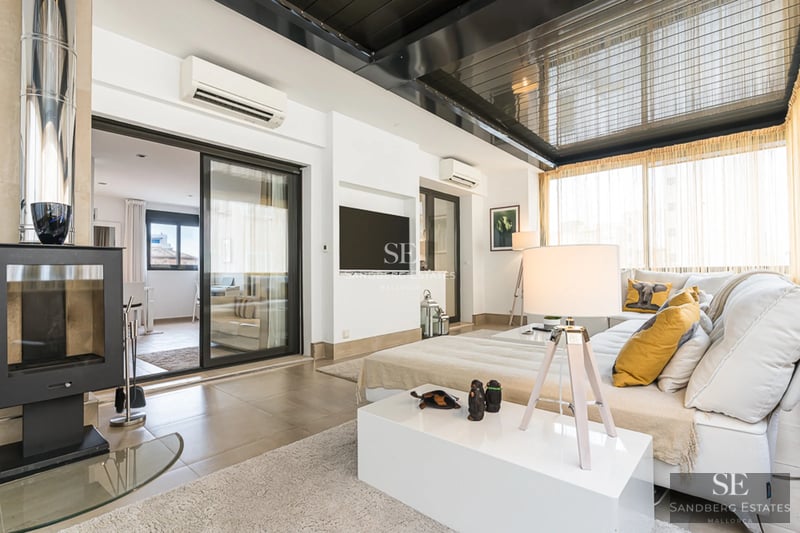 Spacious living room with fireplace, large windows and access to a terrace with views. Modern decoration in neutral tones.