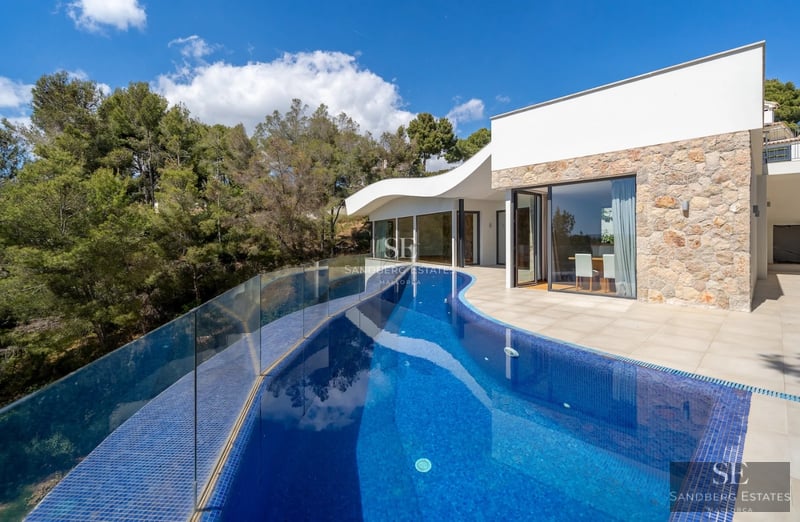 Spacious living room with floor-to-ceiling windows, natural light, minimalist furniture, and access to a terrace with sea views. Modern and elegant design.