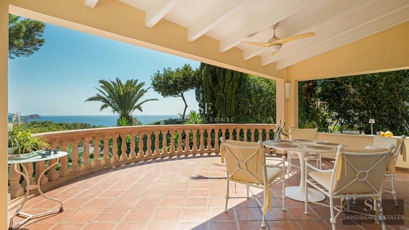 Spacious living room with panoramic windows, light wood floors, beige sofa, and stunning sea view. Modern and bright design.
