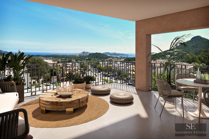 Spacious modern terrace with wicker furniture, a wooden coffee table, and a wide view of the sea and green mountains.
