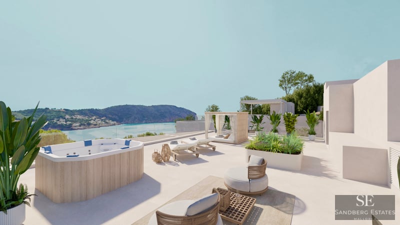 A sunny rooftop terrace with a wood-paneled jacuzzi, sun loungers, and lounge chairs overlooking a coastal bay.