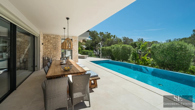 Spacious balcony with panoramic sea views. Modern furniture, glass railing and wooden floor. Elegant and bright design.