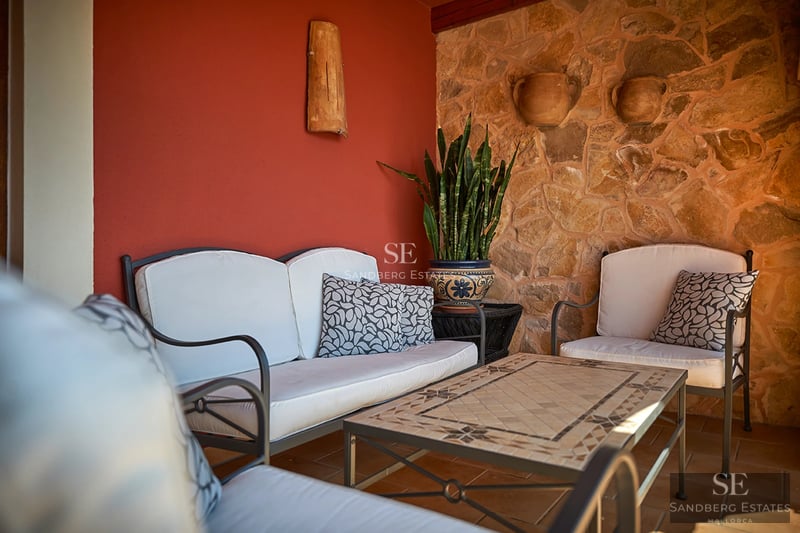 Panoramic view of a villa with an infinity pool, lush garden, and modern architecture. Large windows illuminate the spaces.