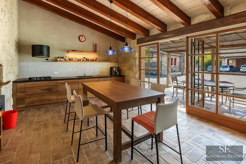 Kitchen with wooden beams, terracotta flooring, and large glass doors leading to an outdoor courtyard.