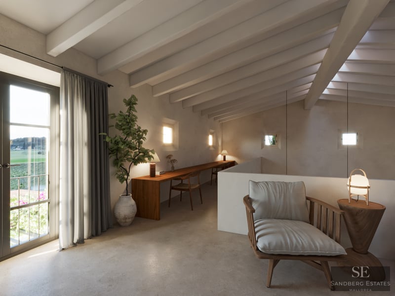 A mezzanine workspace featuring a long wooden desk, exposed white ceiling beams, and a stylish lounge chair by a balcony.