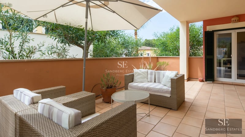 View of a modern villa with infinity pool, designer furniture, and lush vegetation. Large windows and elegant architecture.