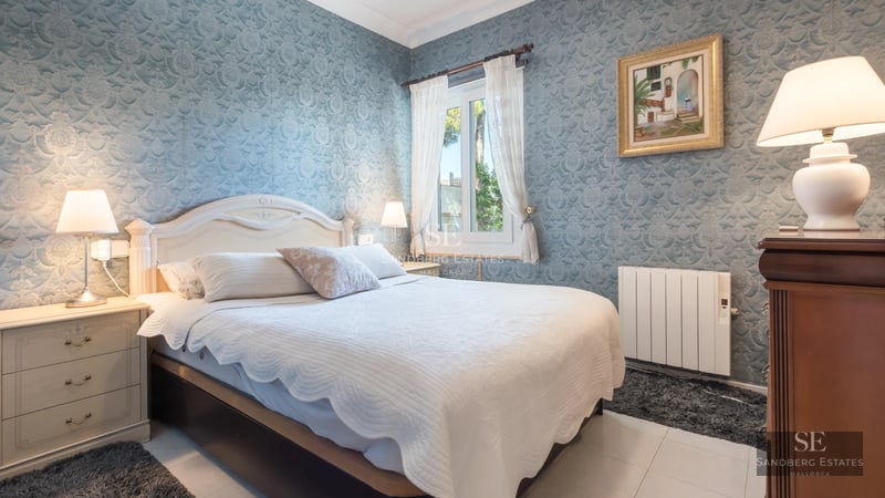 View of a luxurious modern villa featuring an infinity pool, manicured garden, and large windows. Minimalist design and high-quality finishes.