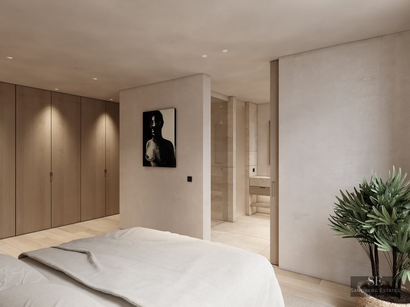 Modern bedroom featuring wood closets, beige walls, and a view into a private ensuite bathroom with stone finishes.