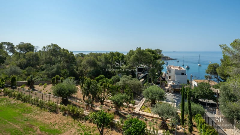 View of a modern infinity pool, surrounded by greenery, with a contemporary design house in the background.