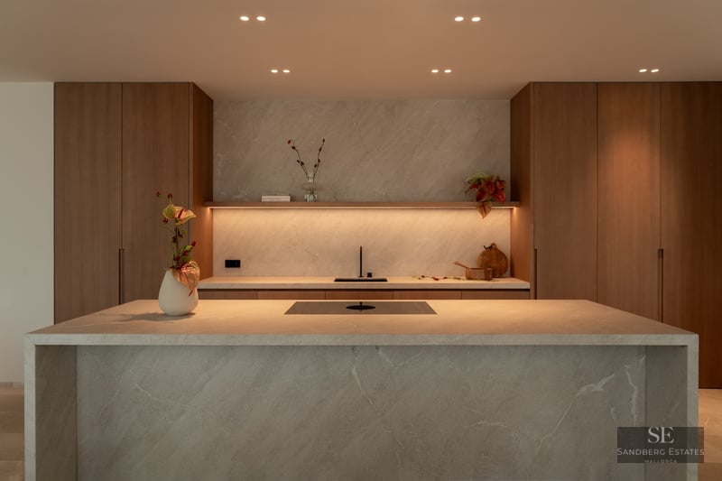 Modern kitchen featuring a large stone waterfall island, warm wood cabinetry, and integrated LED ambient lighting.