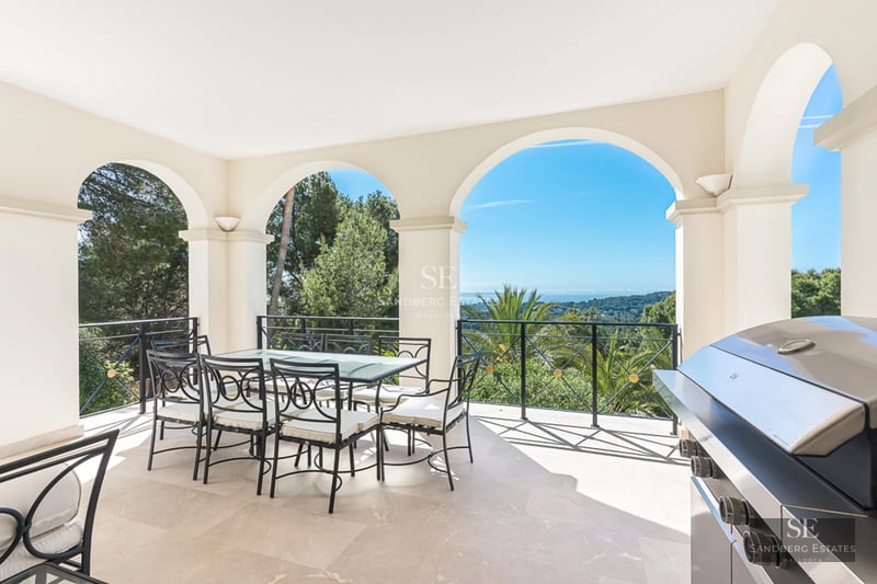 Spacious balcony with panoramic views. Glass railing and wooden floors. Soft lighting. Ideal space for relaxation.