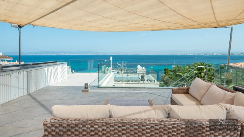 Exterior view of a modern villa featuring an infinity pool, manicured garden, and spacious terraces. Contemporary architecture with large windows.