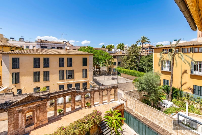 Spacious living room with window walls, leather sofas, fireplace, and built-in shelves. Natural light and garden view.
