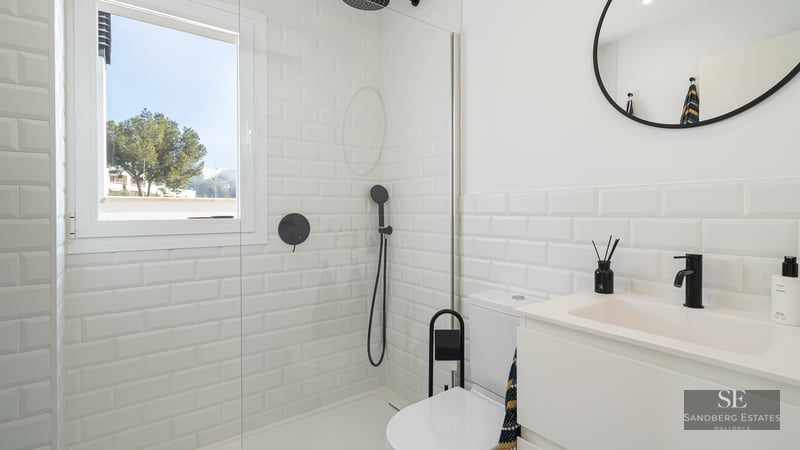 Bright bathroom featuring white subway tiles, a glass shower partition, and modern matte black fixtures.