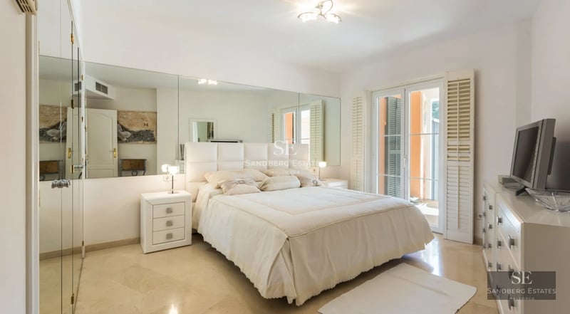 View of the pool, garden, and modern facade of a villa. Clean lines, large windows, and lush vegetation.