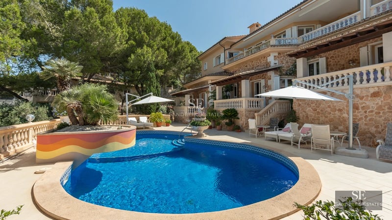 Exterior view of a modern villa with a pool, garden, and minimalist architecture. Natural stone facade and large windows.