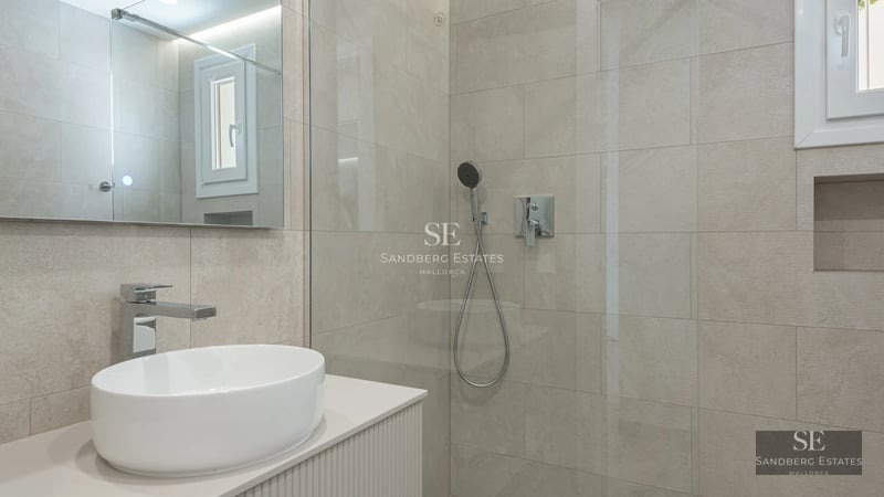 Spacious living room with floor-to-ceiling windows, wood floors, modern furniture, and a stunning ocean view. Luxurious and bright.