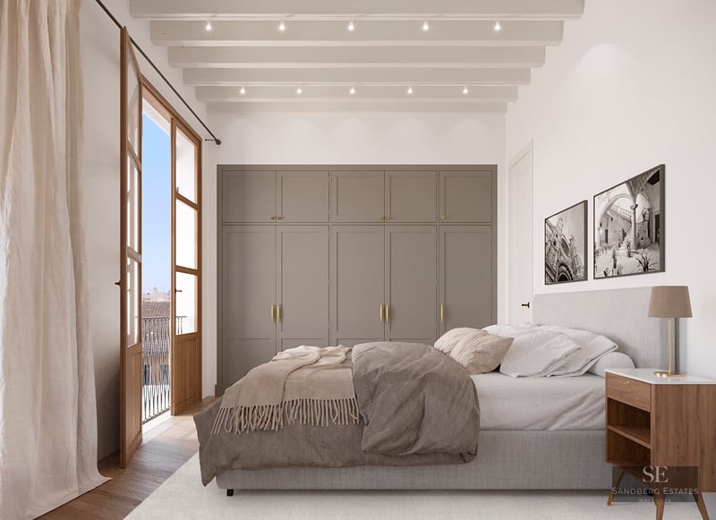 Elegant bedroom featuring wooden French doors, beige built-in wardrobes, and a white beamed ceiling.