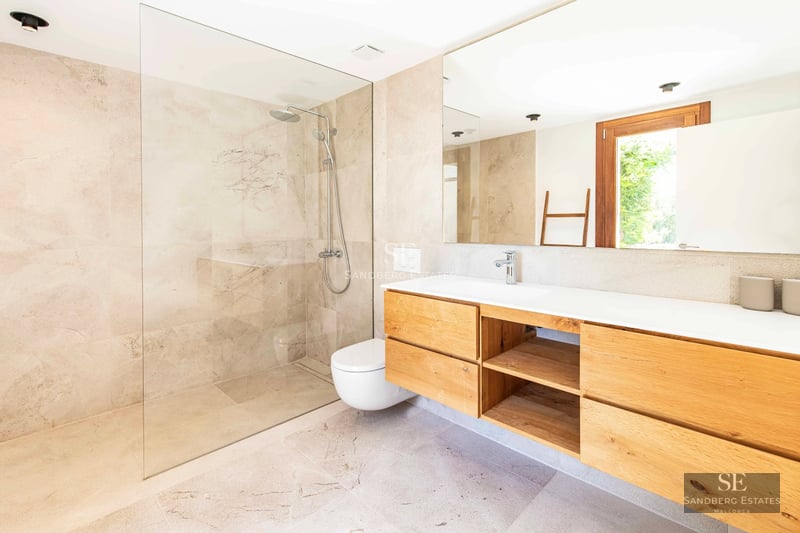 Spacious terrace with an infinity pool and panoramic sea views. Modern and elegant furniture, wooden floors, and glass railing.