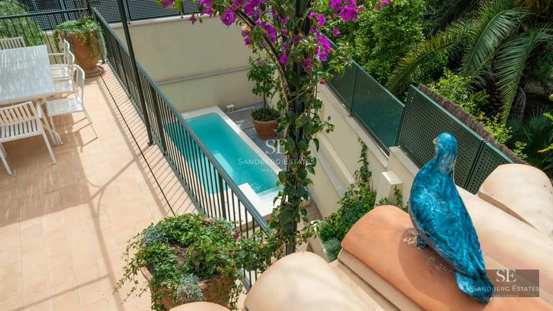 View of a modern villa with infinity pool, lush garden, and expansive terraces. Minimalist architecture and luxury finishes.