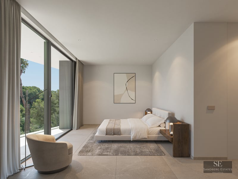Modern minimalist bedroom with floor-to-ceiling windows overlooking trees, a plush bed, and designer armchair.
