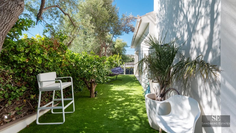 Bright living room with large windows, modern furniture, wooden floor, and a stunning panoramic sea view.