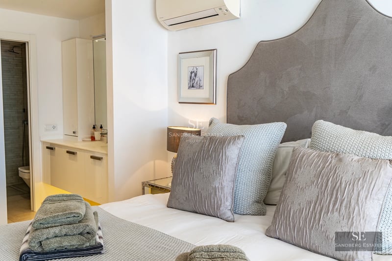 Spacious living room with panoramic windows, light wood flooring, modern design, gray sofas, and access to a terrace with a view. Elegance and comfort.