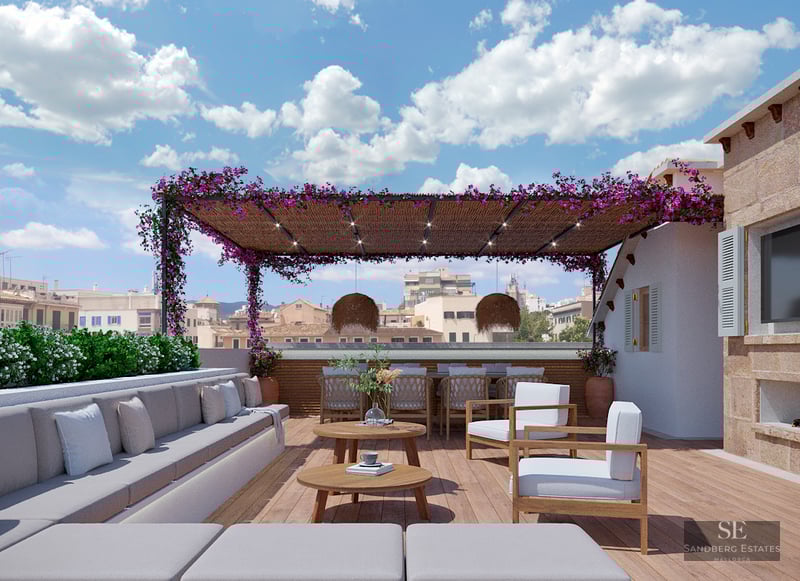 Spacious wooden rooftop terrace with grey sofas, bougainvillea-covered pergola, and outdoor dining area overlooking the city.