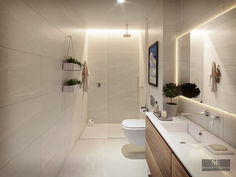 Modern bathroom with beige stone tiles, a glass shower, wood vanity, and a large backlit mirror.