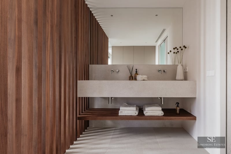 A modern bathroom featuring a floating stone double vanity, a large mirror, and a wall of vertical dark wood slats.