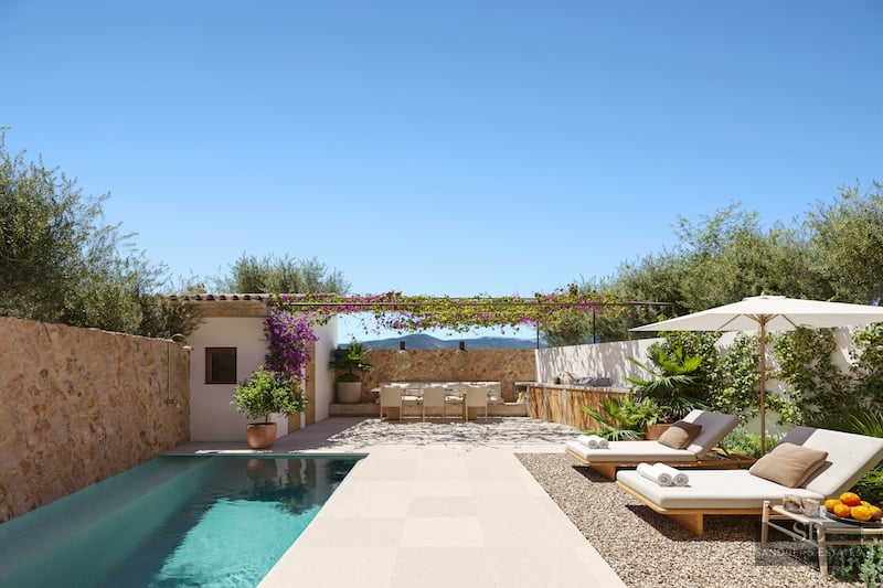 Private pool area with sun loungers, outdoor kitchen, and dining under a pergola surrounded by stone walls.