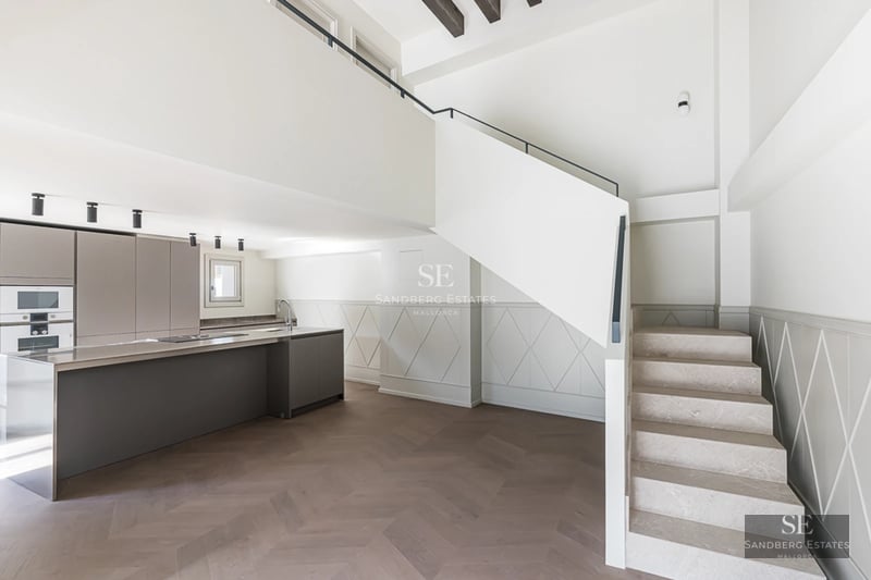 Spacious living room with floor-to-ceiling windows, gray sofas, natural light, and balcony access with views. Modern and elegant design.