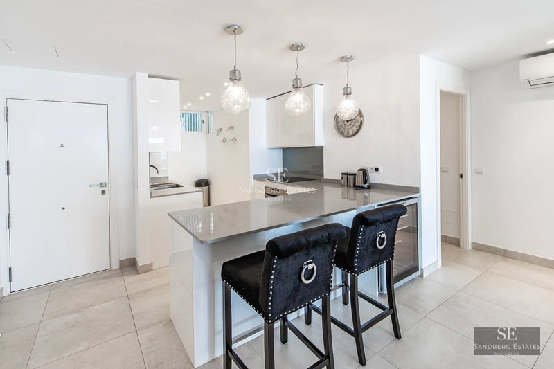 Spacious, bright living room featuring large windows, light wood floors, and modern furniture. Panoramic outdoor views.