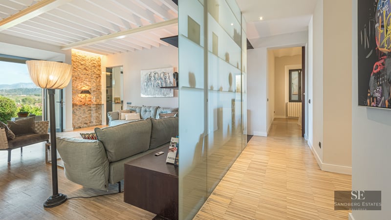 Living room featuring a grey sofa, wooden floors, a natural stone wall, and a frosted glass partition.