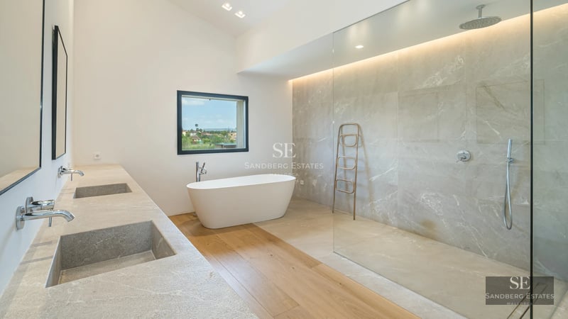 Spacious living room with panoramic sea view windows, beige sofas, light carpet and modern decor. Natural lighting and stunning views.