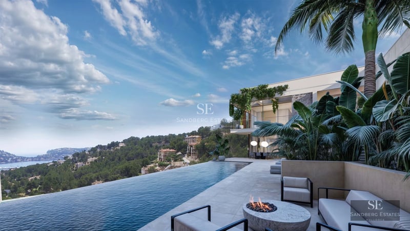 View of an infinity pool with sun loungers and a modern villa featuring large windows. Lush vegetation and clear sky.