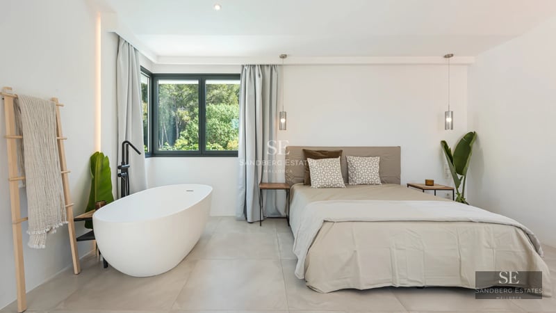 View of a modern villa featuring an infinity pool, large windows, and lush greenery. Minimalist design with high-quality finishes.
