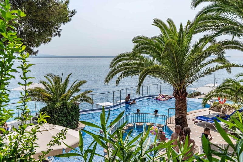 Exterior view of a modern villa with pool, landscaped garden, large windows, and minimalist design. Ambient lighting.