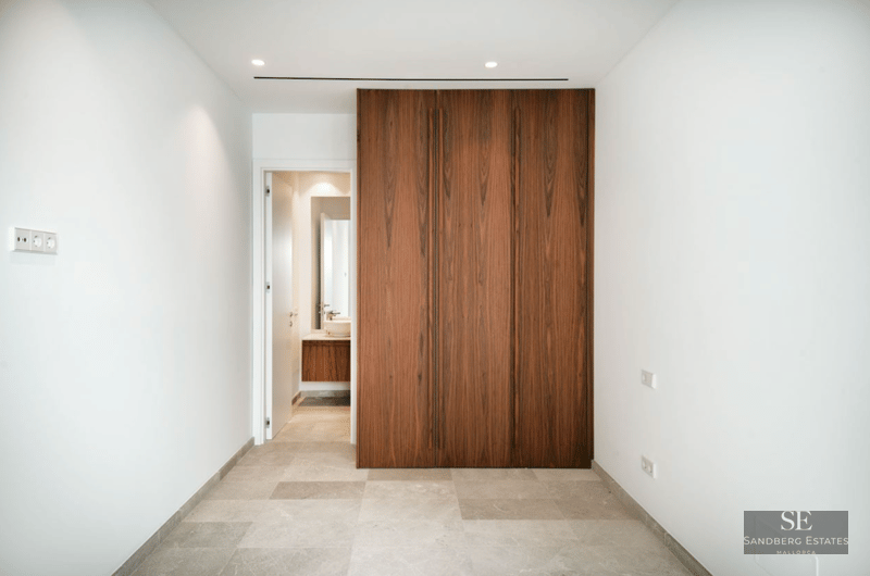 Large floor-to-ceiling dark wood closet next to a white doorway leading to a modern bathroom.