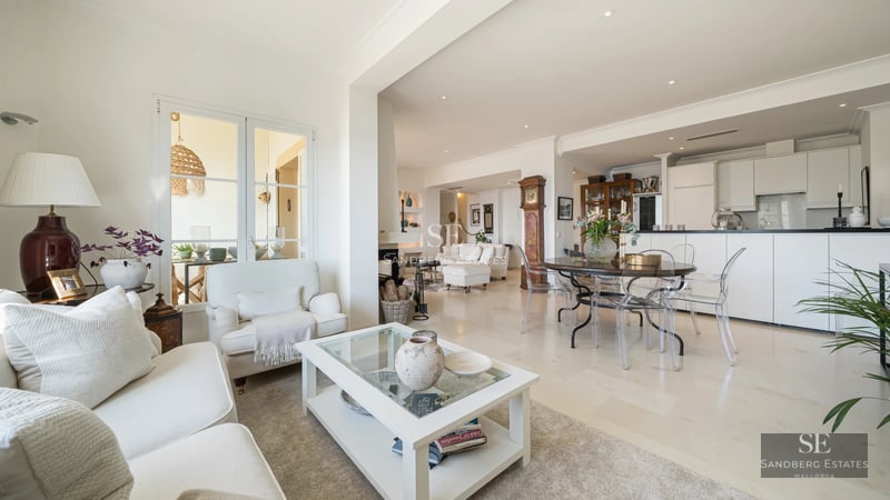 Spacious balcony overlooking the sea. Modern outdoor furniture. Glass railing. Warm lighting. Relaxing area. Sun loungers.