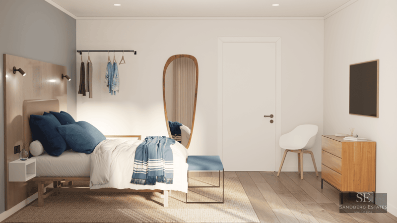 Chambre lumineuse avec lit en bois, literie bleue, miroir de forme organique et meubles en bois clair.