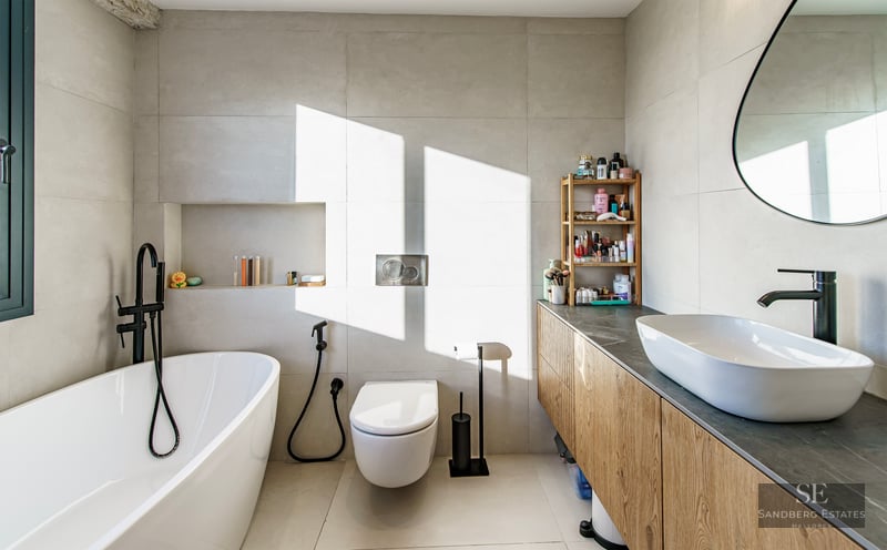 Bright modern bathroom featuring a white freestanding tub, wood vanity with vessel sink, and matte black fixtures.