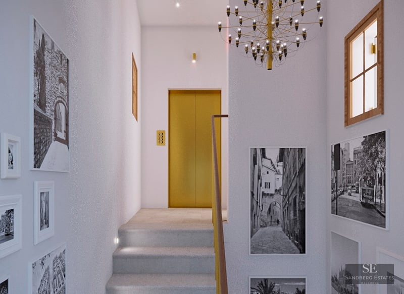 Modern hallway with stone stairs, a gold-finished elevator, black and white wall art, and a designer chandelier.
