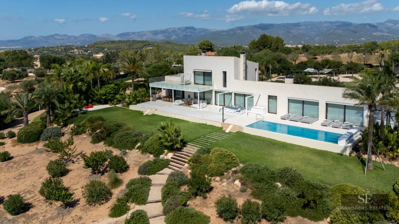 Exterior view of a modern villa featuring an infinity pool, large windows, and lush gardens. Minimalist architecture.