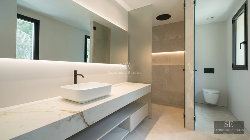 Image of an elegant pool with sun loungers and umbrellas, surrounded by gardens and with a modern building in the background.