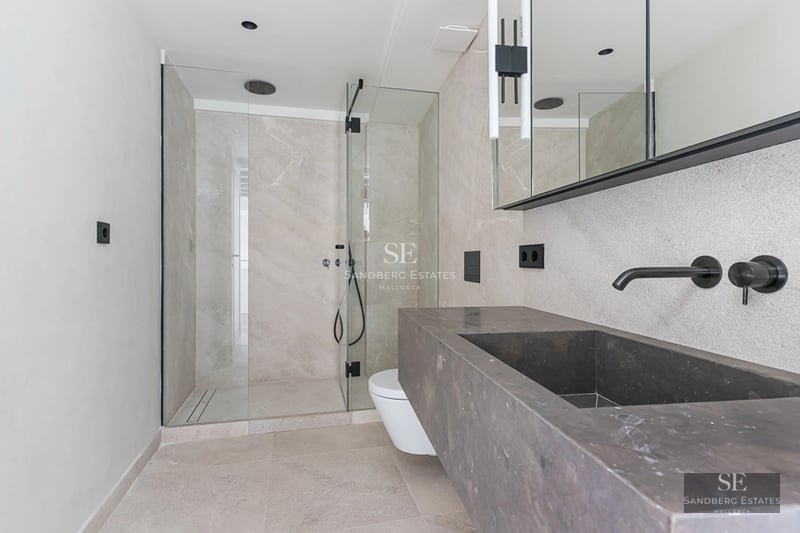 Spacious living room with floor-to-ceiling windows, fireplace, and garden view. Modern sofas and elegant decor. Abundant natural light.