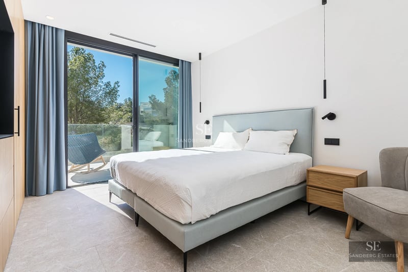 Grand balcon avec vue sur mer. Mobilier moderne, planchers en bois et rambarde en verre. Éclairage ambiant doux.