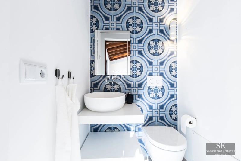 Exterior of modern villa with reflecting pool, palm trees, and minimalist architecture. Clear blue sky.